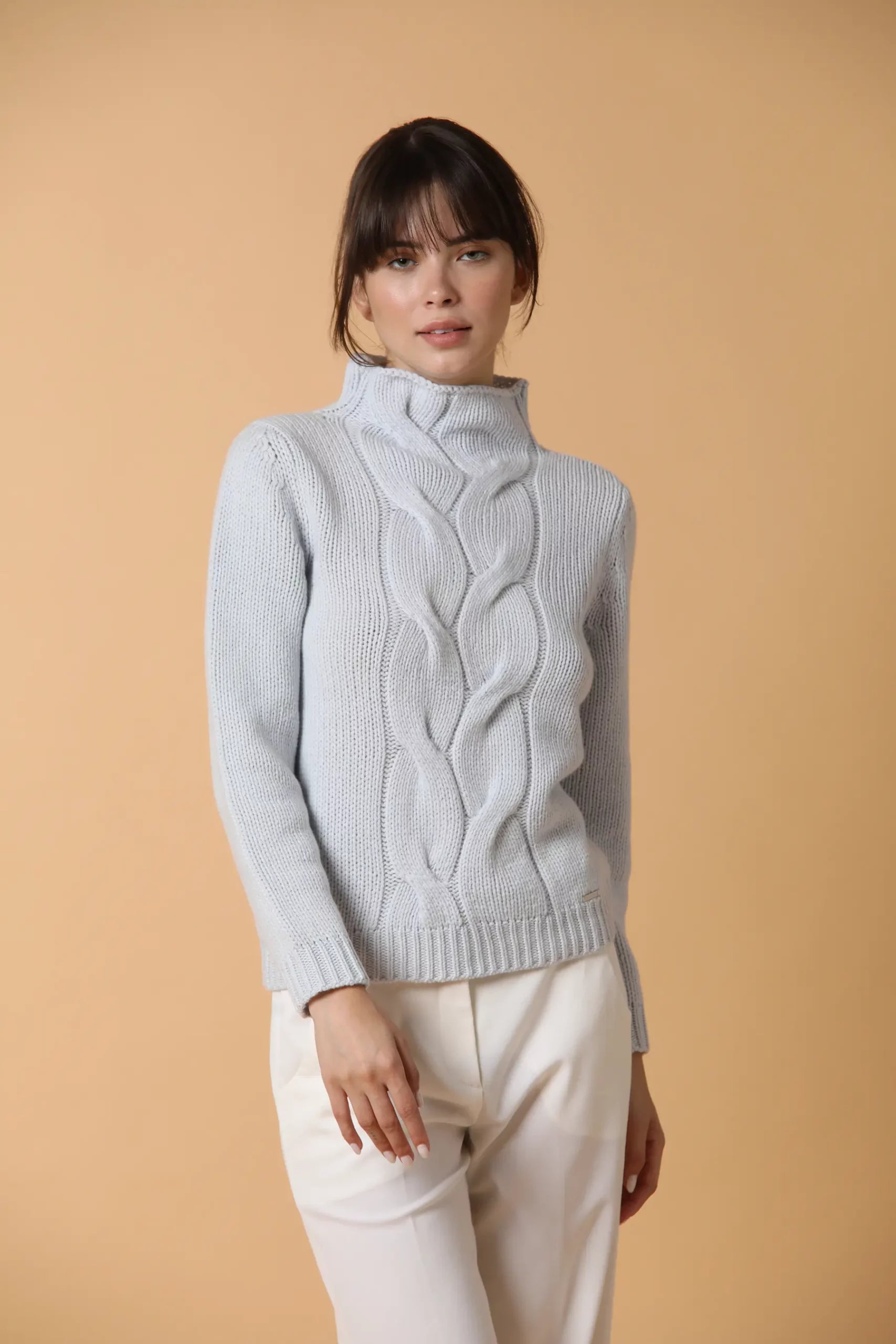 Maglione con collo cratere in punto decorato da due trecce centrali. E’ un basico con uno spunto di personalità, morbido grazie alla sua composizione 100% cashmere. Colore Celeste.