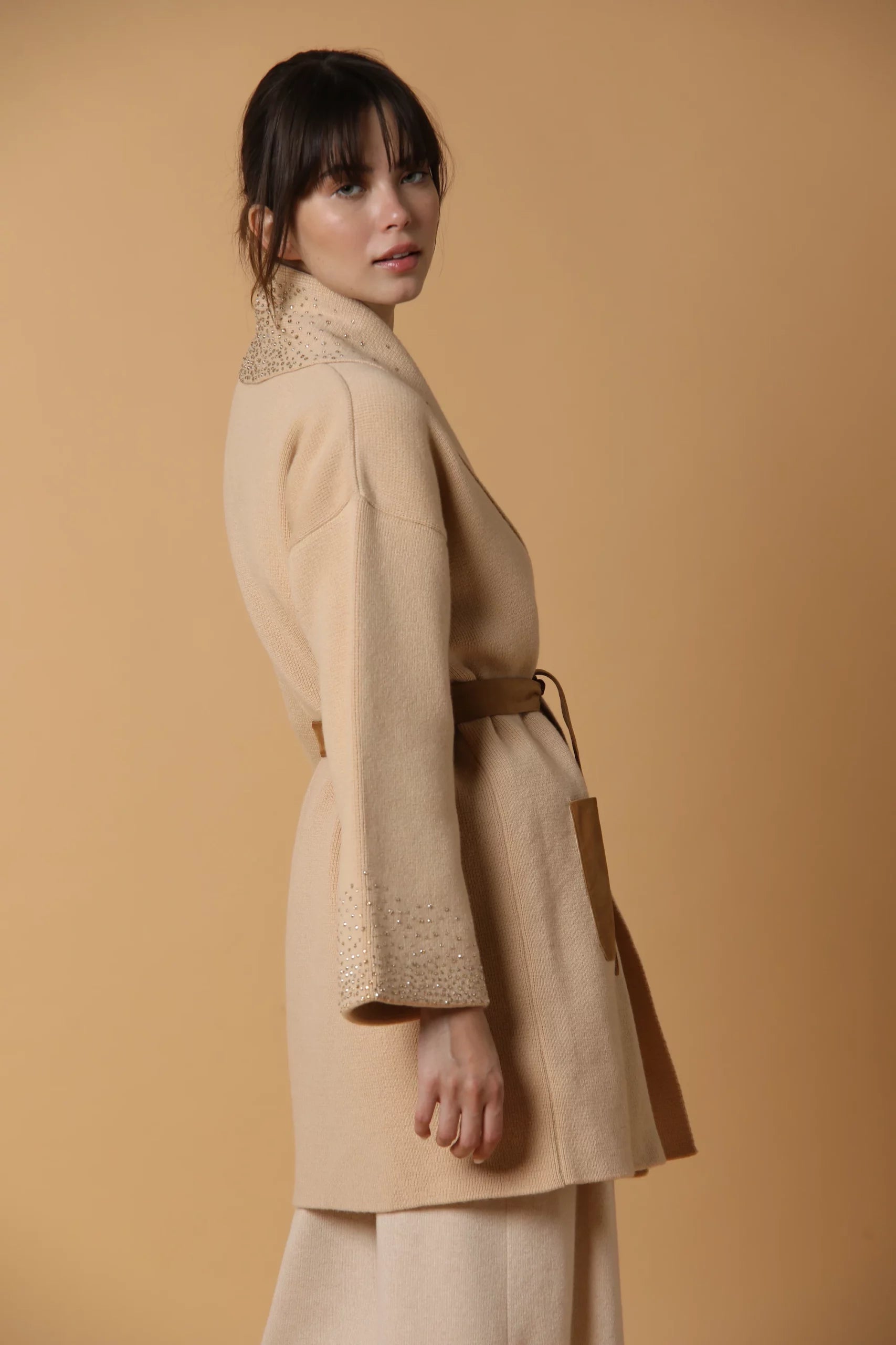 Cappotto in maglia di cashmere, con fodera in seta, tasche in suede ed applicazione di Swarovski. Color cammello.