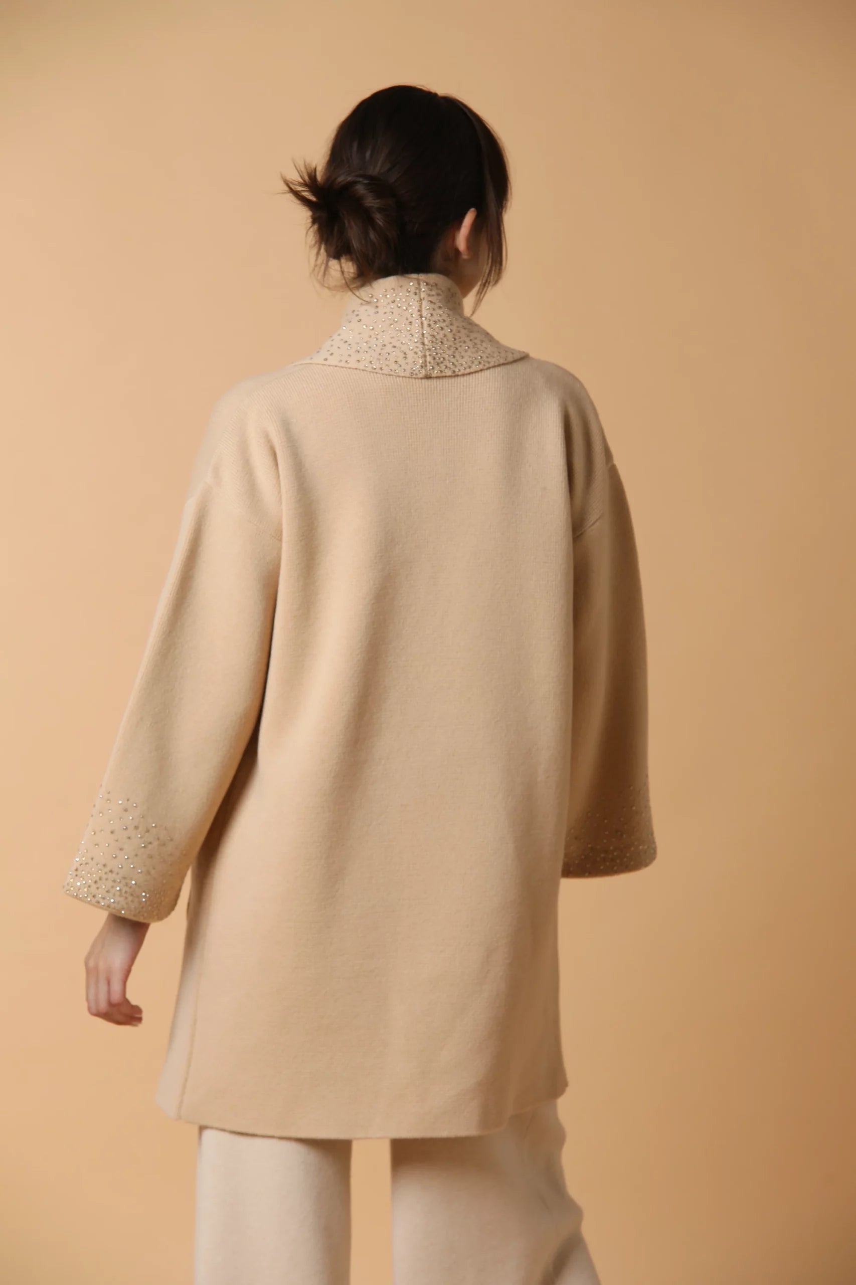 Cappotto in maglia di cashmere, con fodera in seta, tasche in suede ed applicazione di Swarovski. Color cammello.